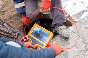Plumbers Checking Sewer Manhole With Borescope Inspection Camera